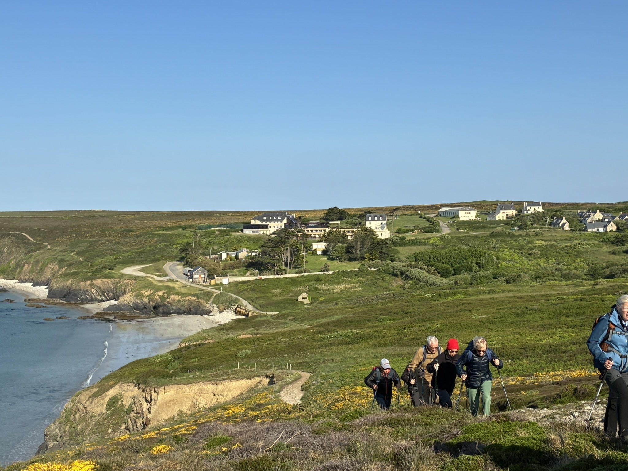 Au fond, on voit le village vacances et nous montons entre lande et falaises .
