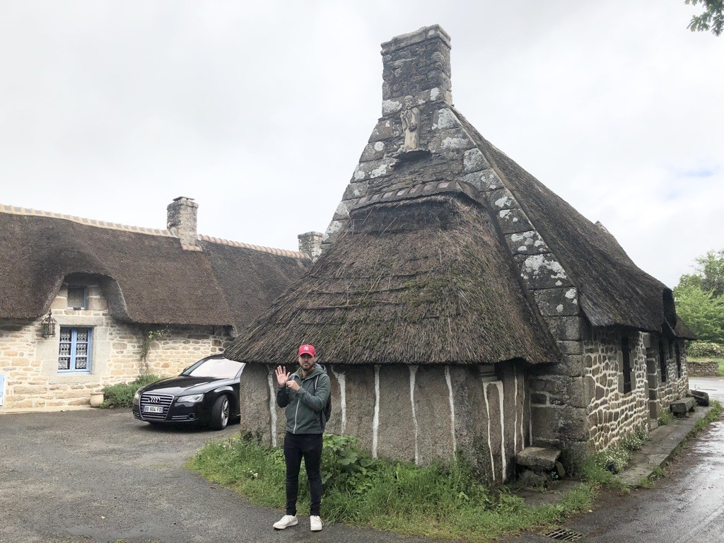 Pierre prend la même pose que la statue du saint située sur la chaumière !